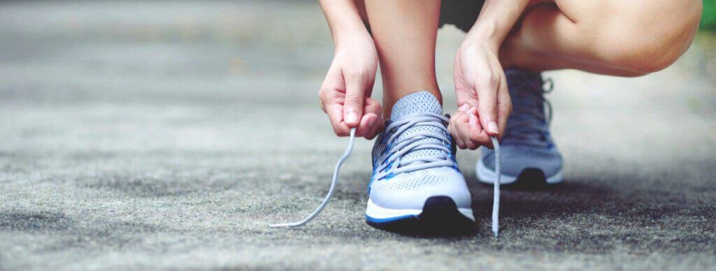 A close-up of sports shoes being laced up before another run, signifying taking the first step to progress.